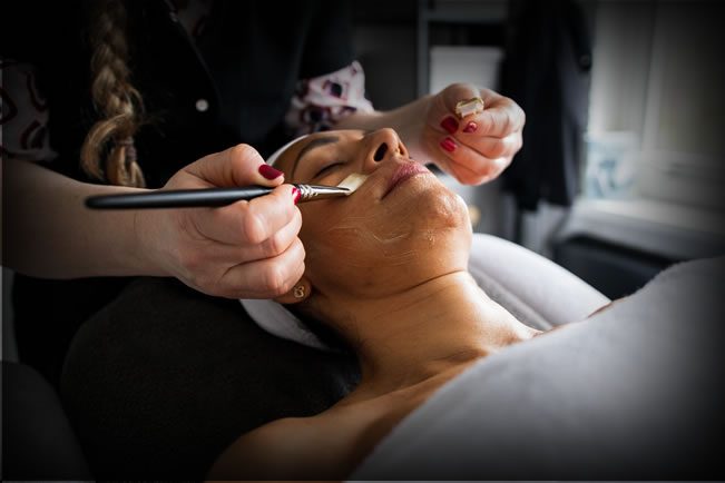 Schoonheidsspecialist brengt een gezichtsmasker aan in de Spa Boutique van XFitClub Huizen